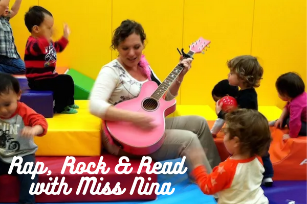 Musician Miss Nina playing a pink guitar with children around her